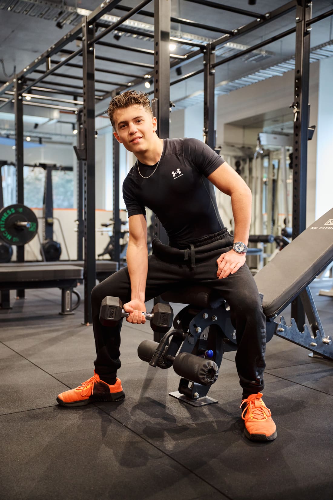 A student doing a dumbbell curl in the school gym