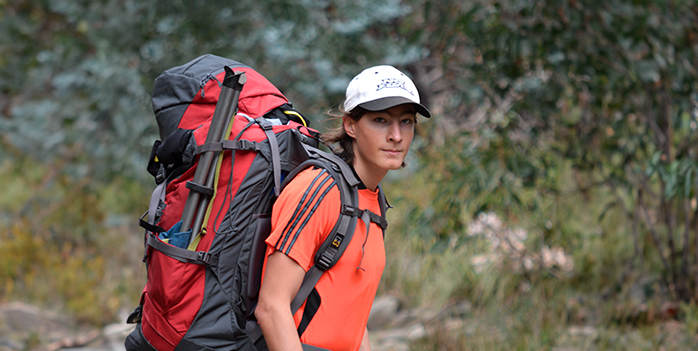 A student hiking with a large pack at Survival Camp